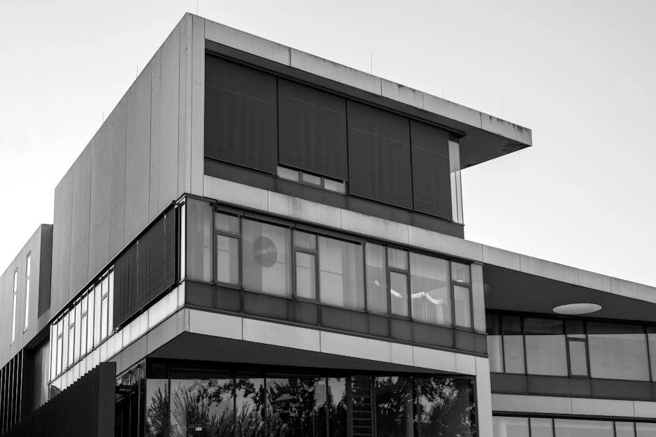 Moderno edificio con facciata in vetro e elementi in legno, circondato da vegetazione urbana